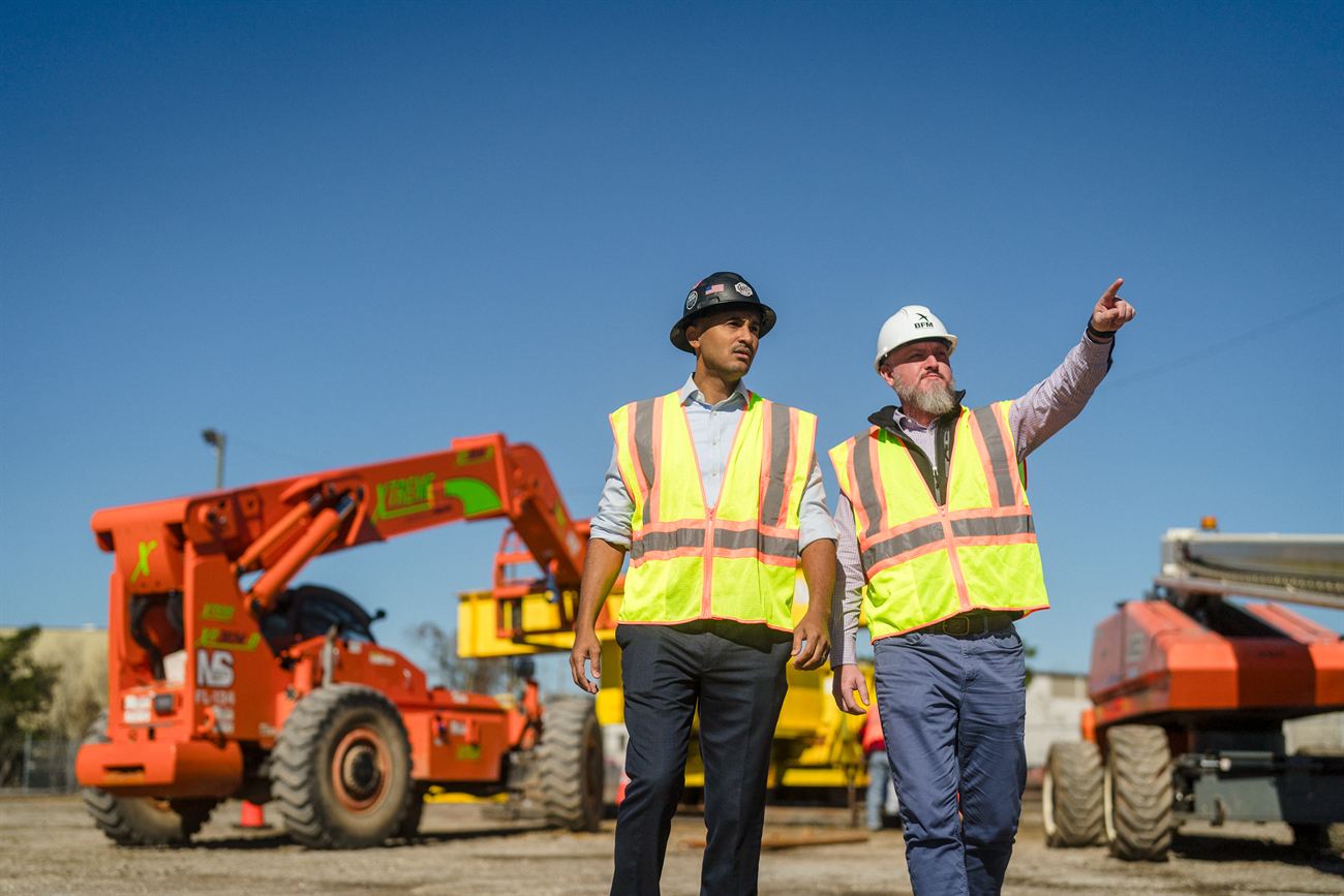 Shomari Figures touring a job site in hard hat and safety vest